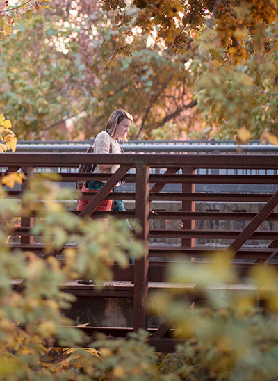 Student walking across a bridge on campus