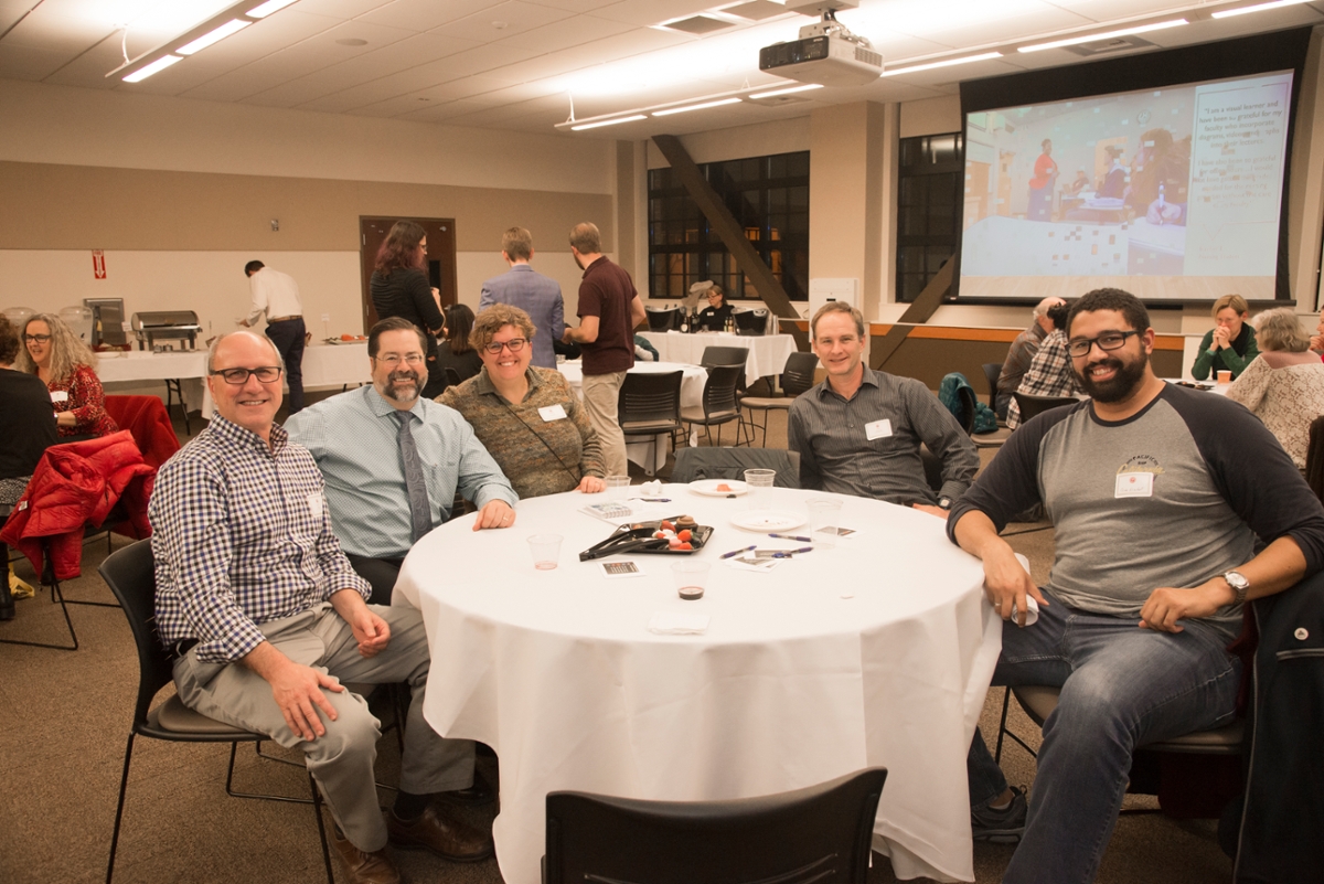 faculty sitting down at a table and smiling during the 2018 Newly Promoted Faculty Reception.