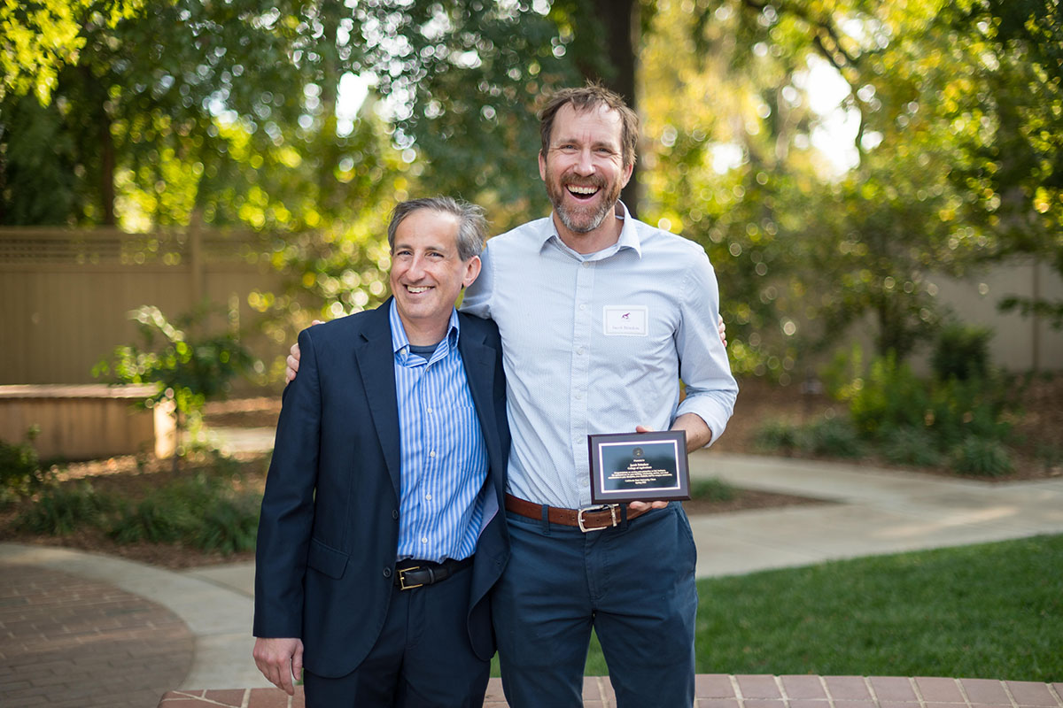 faculty smiling and holding award plaque during the 2022 tenure and promotion faculty reception.