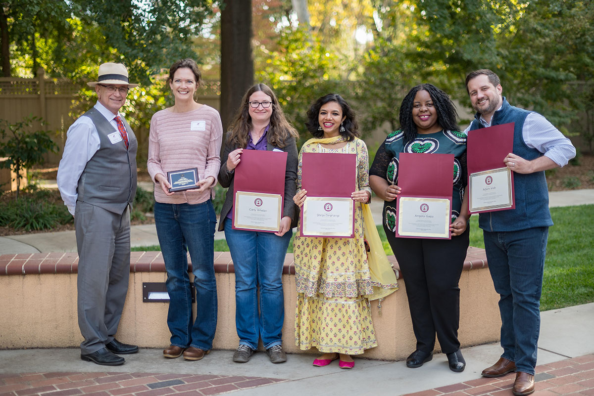 faculty smiling and holding their awards and plaques they received during the 2022 tenure and promotion reception