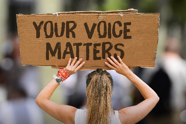 Protestor holding up a cardboard sign that reads "Your Voice Matters"