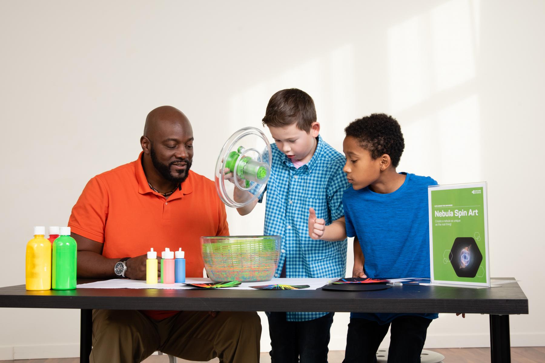 An adult and two children work at a table making science art