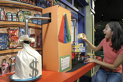 A woman interacts with the Moneyville exhibit