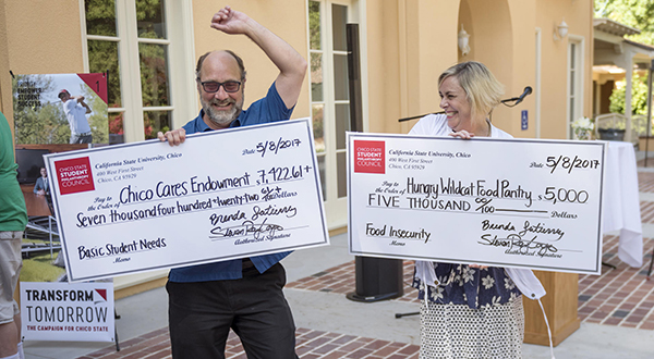 Two people celebrate receiving a giant novelty check