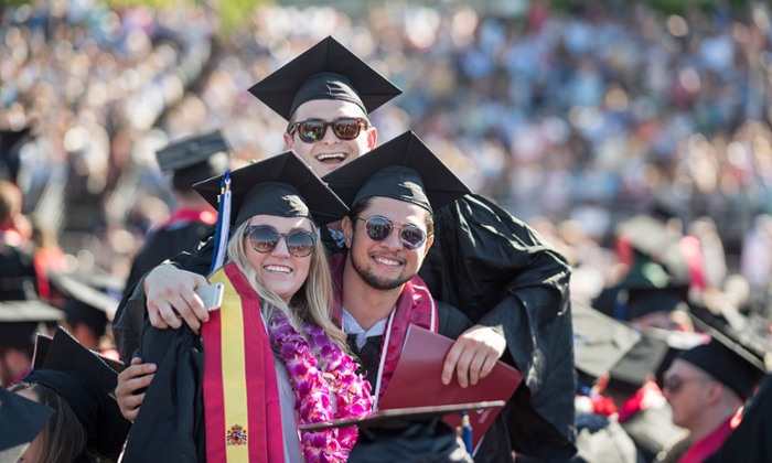 Three graduating students hugging at the Chico State graduation ceremony 