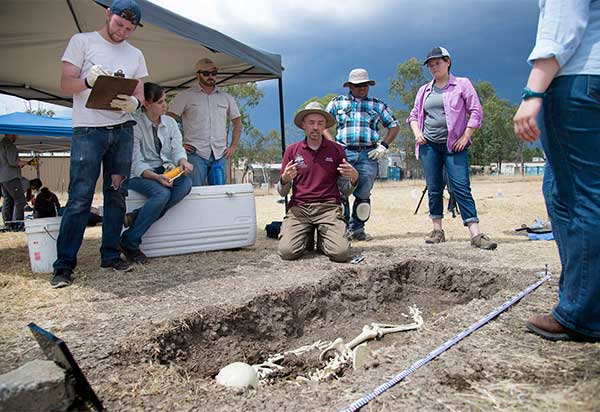 archaeology students with professor out on a dig