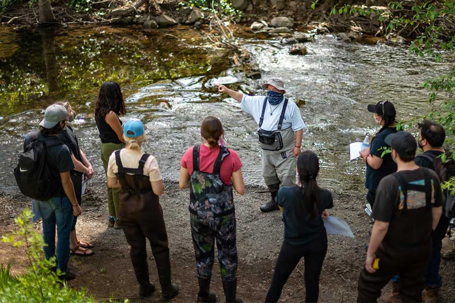 instructor with students next to creek
