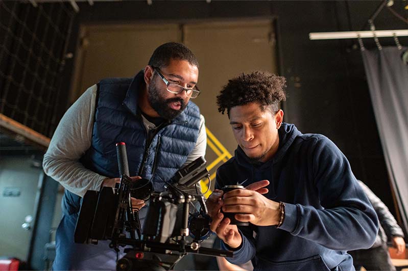Two people work on a film set adjusting specialized equipment.