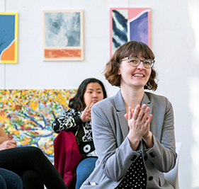 Lecturer Rebecca Shelly (center) applauds the Introduction to Painting students that present their final critique in the Arts Building Critique space 
