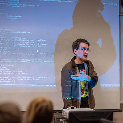 Individual presenting in front of projected code.