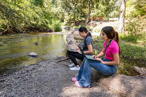 Two girls studying alongside the creek