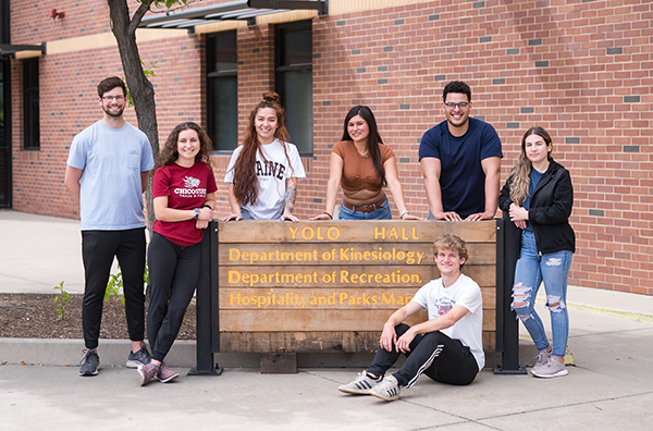 Students sitting around a university sign