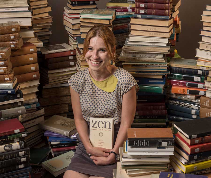 Friederike Fichtner has a portrait taken in the midst of 1000 books as part of the new faculty portraits