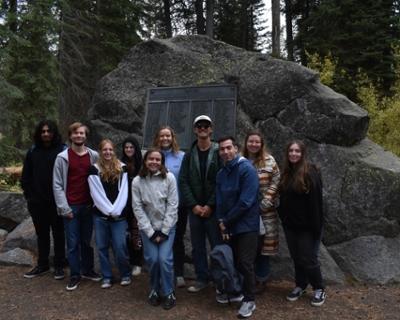students pose for picture in front of memorial placard at Donner Memorial State Park