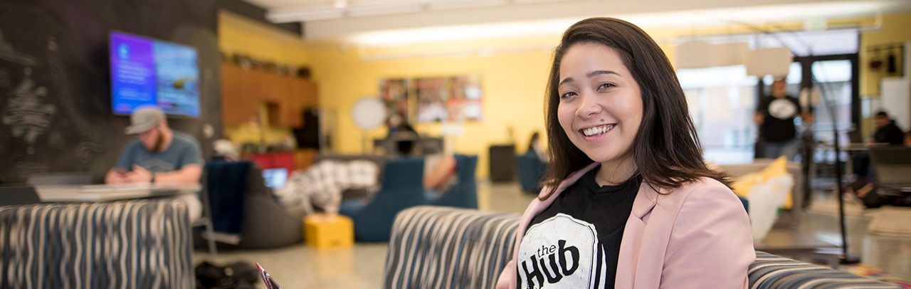 smiling student within the Hub - a common space at University Housing