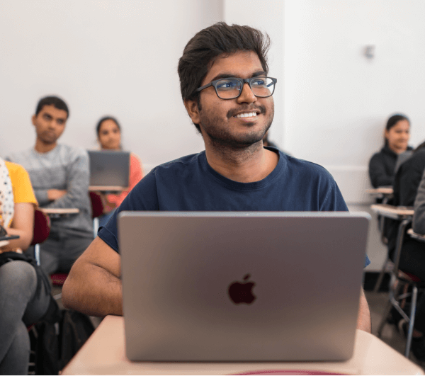 Smiling student using a laptop in class
