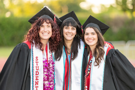 3 females hugging and smiling in graduation