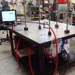 Table with multiple attachements, computer monitor, and hose being formed.