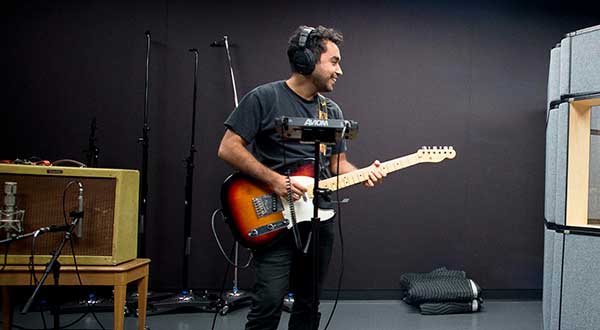 A MUTA student playing electric guitar in the studio.
