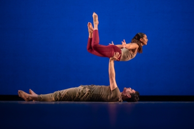 Male dancer horizontal on floor lifting a female dancer into the air