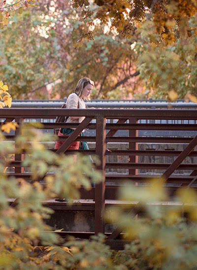 student walking across bridge on campus