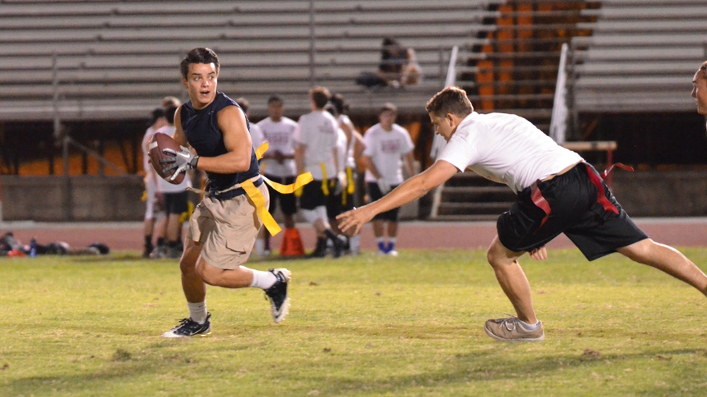 Two people playing flag football. One is trying to remove flag as the other person looks for an open teammate.