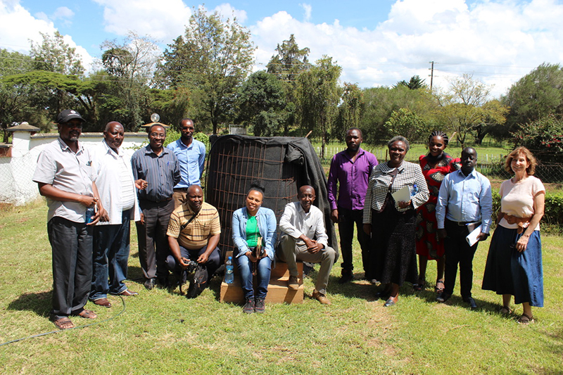 A group of people posing in front of the bioreactor they built in Kenya.