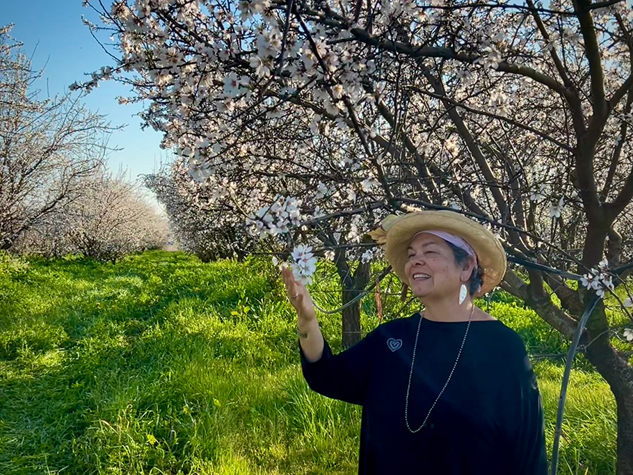 Rosie Burroughs in a flowering almond orchard with cover crops
