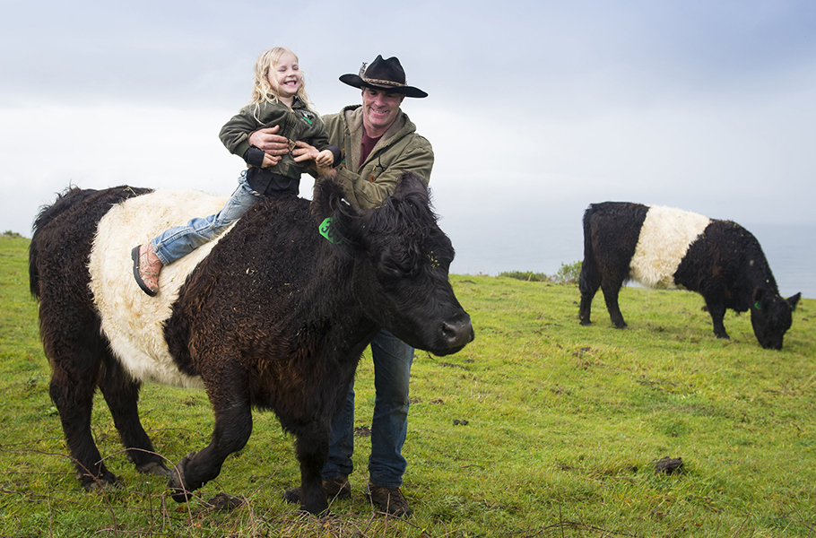 Eric Markegard with one of his children who is riding a cow.
