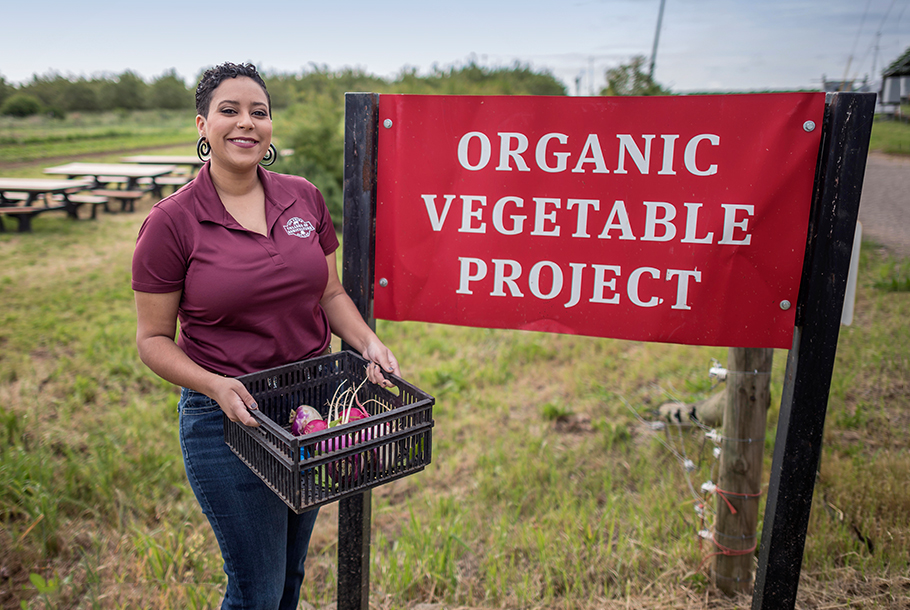 College of Ag graduate Kaeli McCarther next to the Organic Vegetable Project sign.