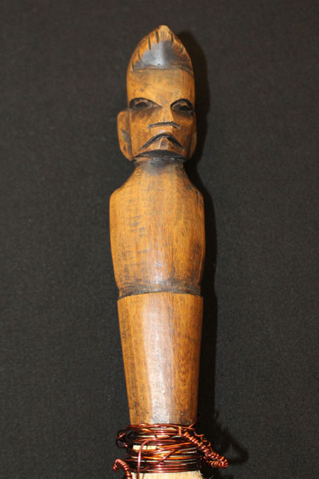 handle of fly swatter with a man's face carved into it