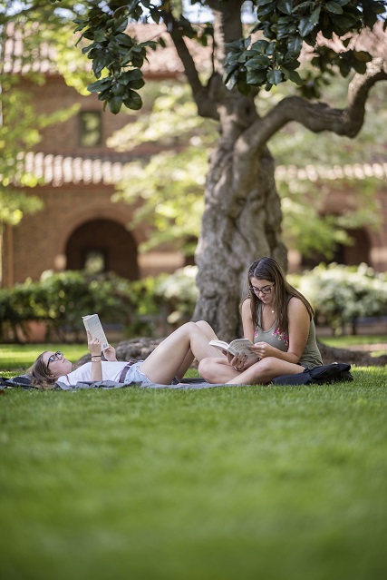 Two people reading books on the Kendall lawn.