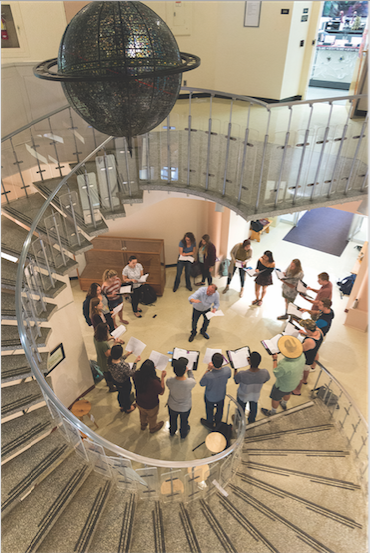 Looking down from a spiral staircase at a circle of people singing