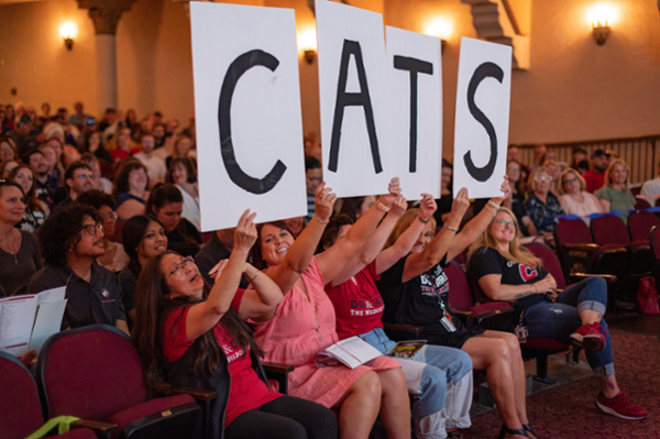 full audient at Laxson auditorium, several people hold up posters spelling CATS