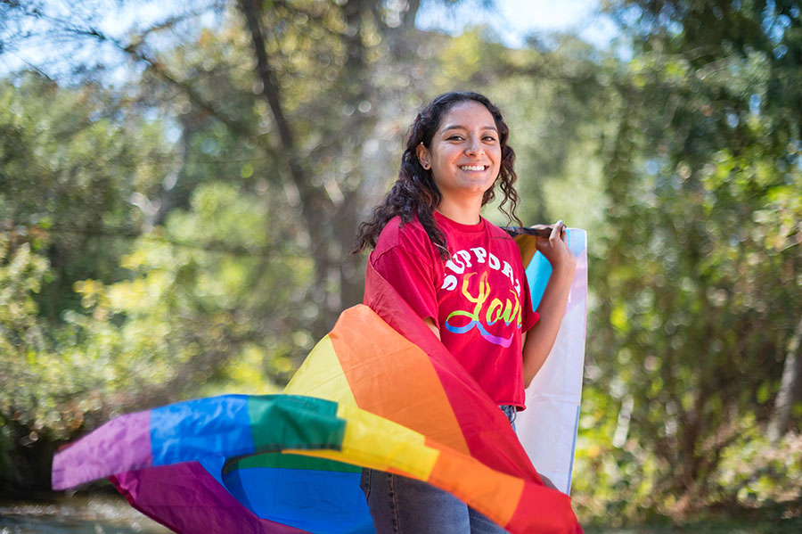 student wrapped in pride flag
