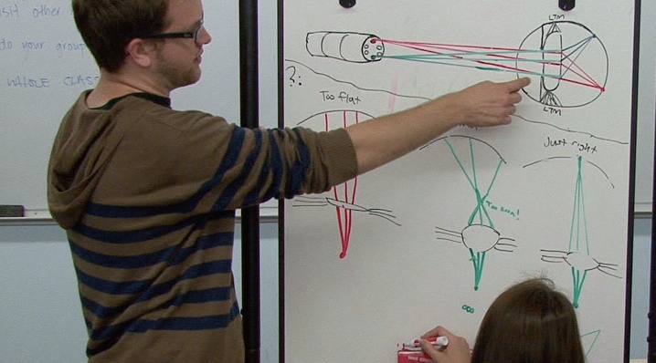 student pointing to diagram on a white board