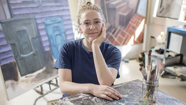 A painting student pauses in front of her work