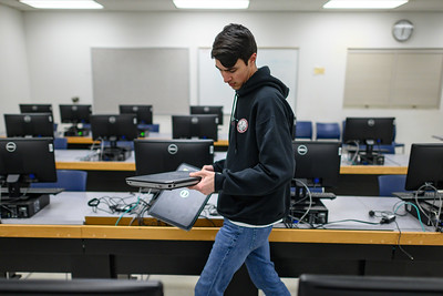 Staff walking inside a computer lab while he holds a laptop.