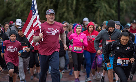 Mike Guzzi carries the American flag during Veterans Day 5k run