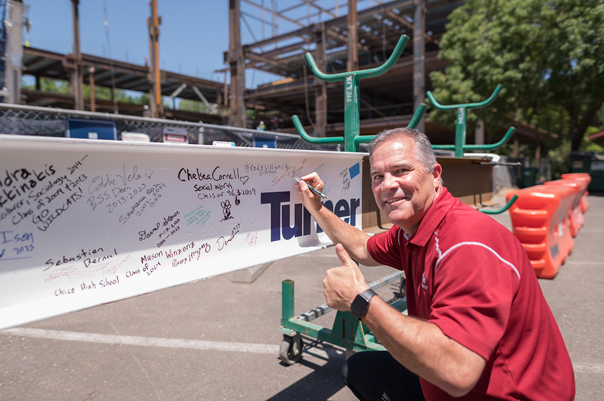 Interim Provost Perez signs a beam going into the new BSS building