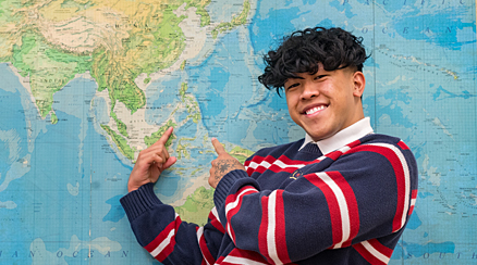 A student poses in front of a map
