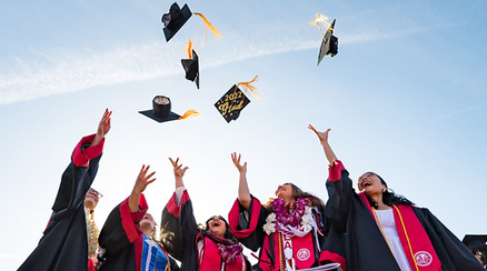 Graduate students toss their caps into the air.